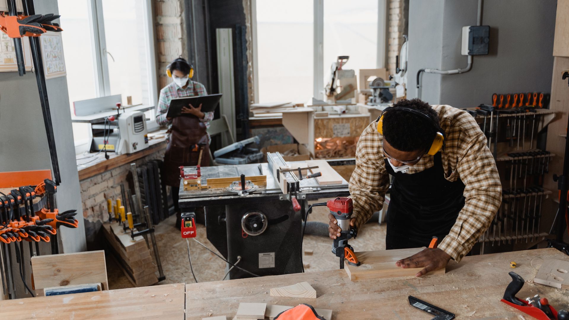 Black carpenter using a router safely at a workshop bench