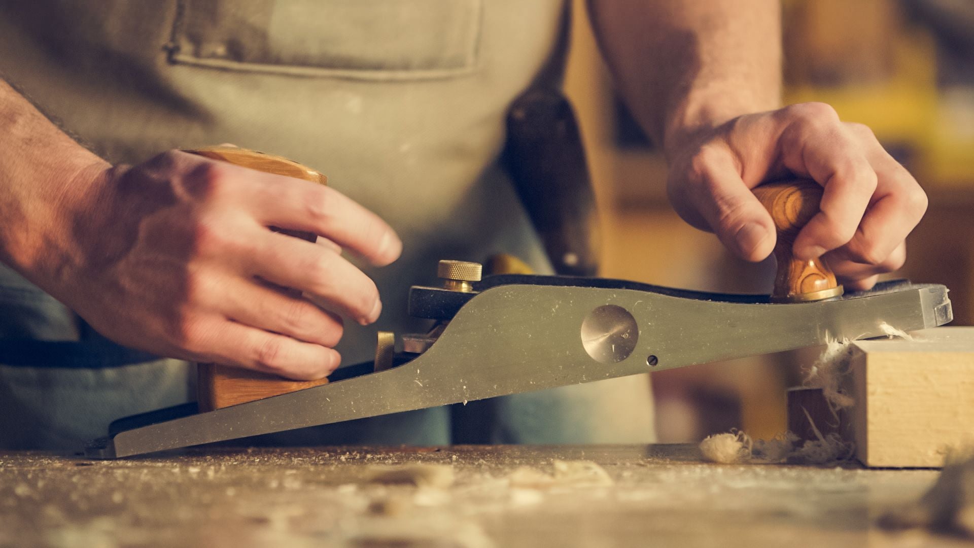 Close-up of a craftsperson setting a hand plane on timber